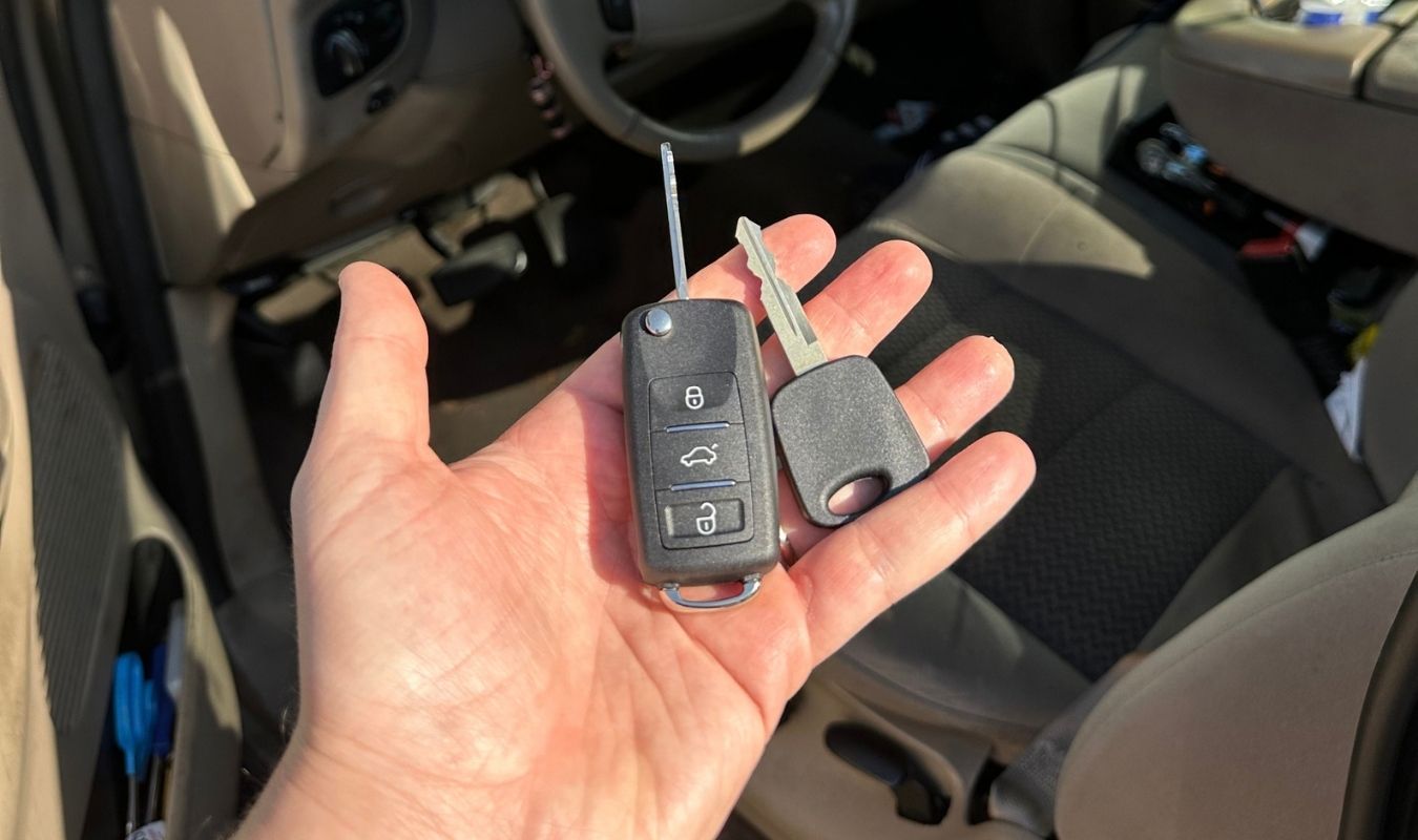 Replacement transponder key and remote flip key held in front of a 2001 Ford F-150 in Bradenton