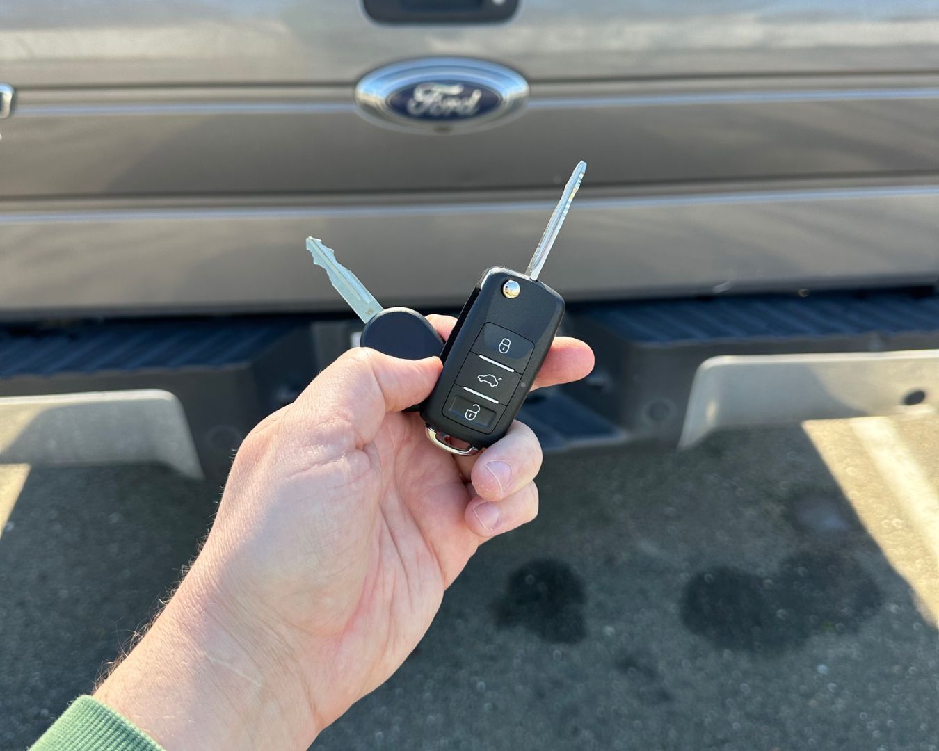 Replacement flip key and standard spare held in front of a 2012 Ford F-150