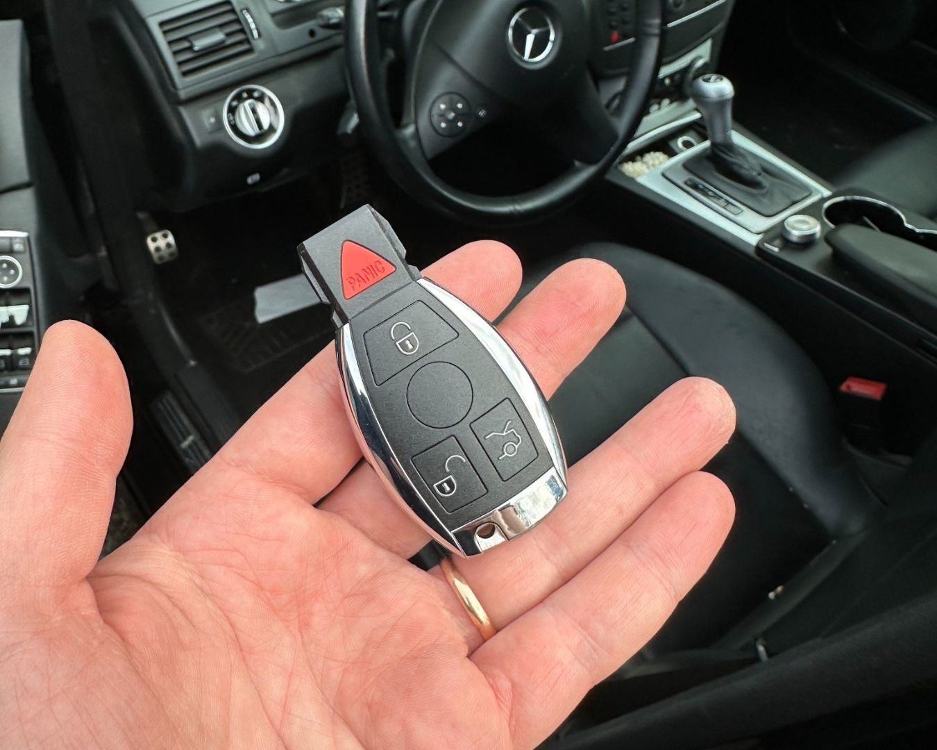 Replacement key held beside the interior of a 2013 Mercedes C300 during an all-keys-lost service in Sarasota.